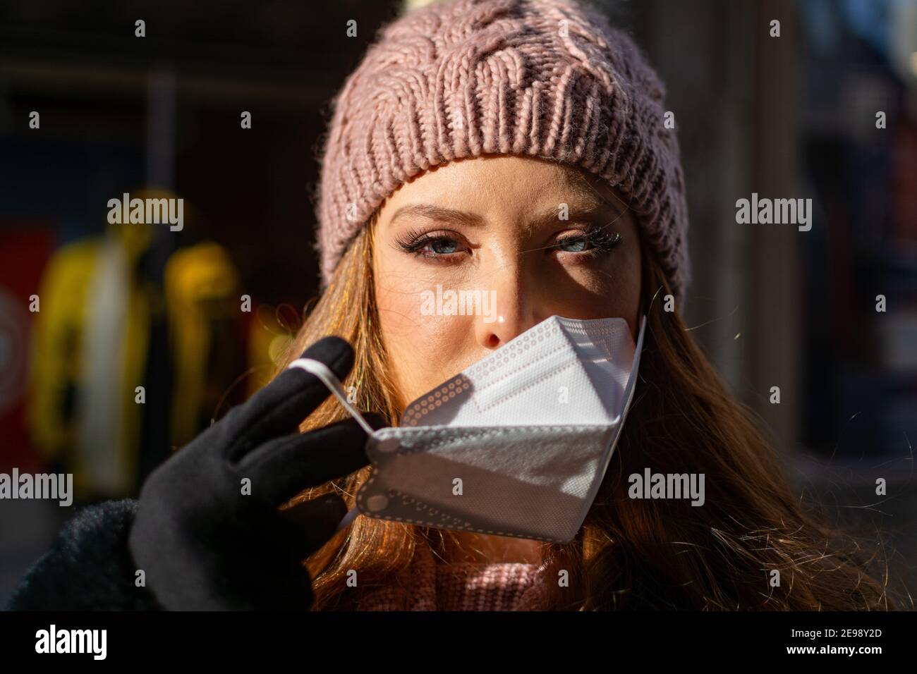 Bonne jeune femme avec les yeux bleus et les cheveux de gingembre en retrait Un masque protecteur pour le visage (FFP-2) pendant la pandémie de COVD-19 Banque D'Images