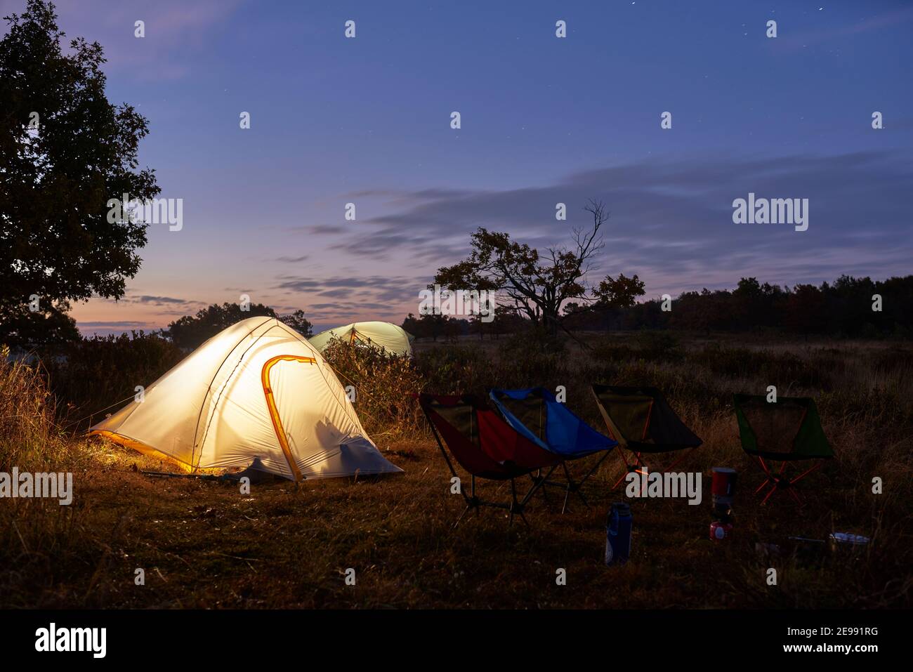 Illuminé les tentes de remballage dans le champ juste avant le lever du soleil. Banque D'Images