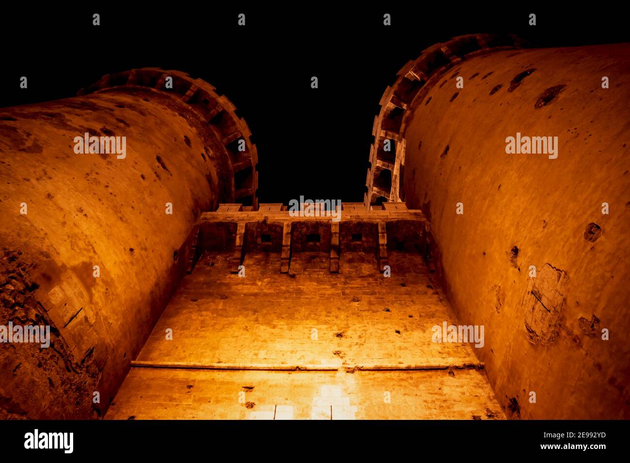 le fort médiéval domine « Torres de Quart » avec des prises de vue de canon visibles dans la nuit illuminée d'orange à Valence, Espagne Banque D'Images