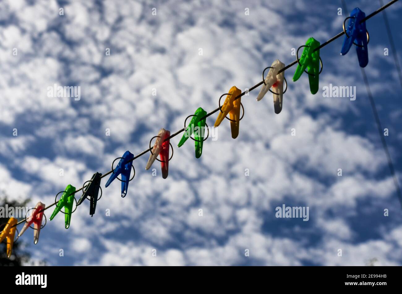 Épingles à linge colorées sur une corde à l'arrière-plan d'un ciel bleu avec nuages Banque D'Images