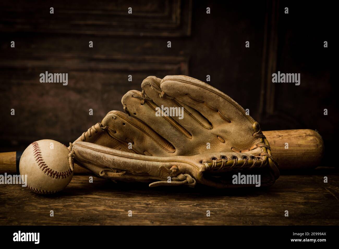 Vieux gant de baseball en cuir couché sur une table antique avec balle et batte Banque D'Images