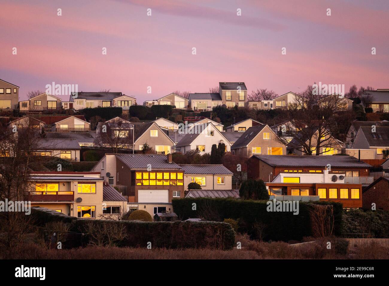 Lever de soleil reflétant la lumière dorée des maisons de Dalgety Bay, Fife, Écosse Banque D'Images