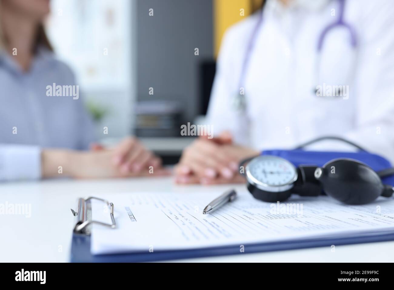 Tonomètre et presse-papiers avec antécédents médicaux à proximité de la table médecin et patient Banque D'Images