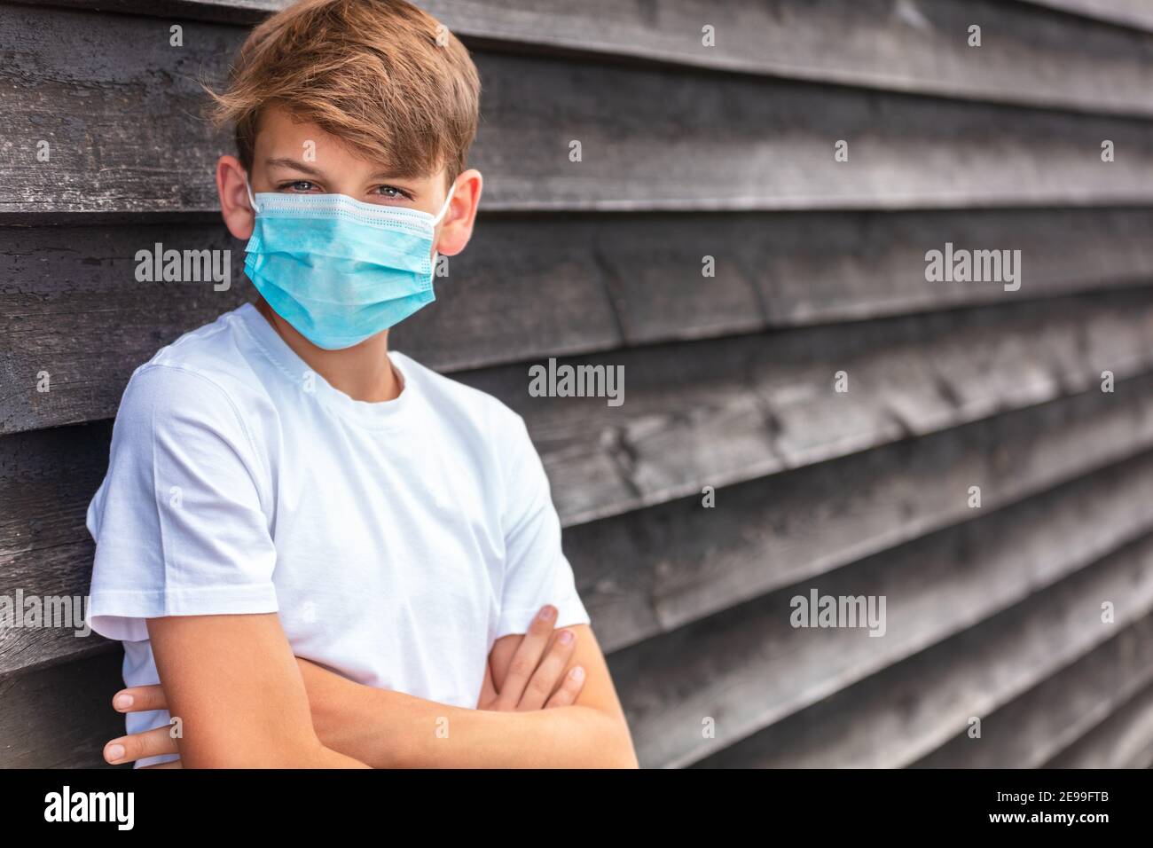 Garçon adolescent garçon enfant mâle portant un masque facial à l'extérieur pendant la pandémie du coronavirus COVID-19 Banque D'Images