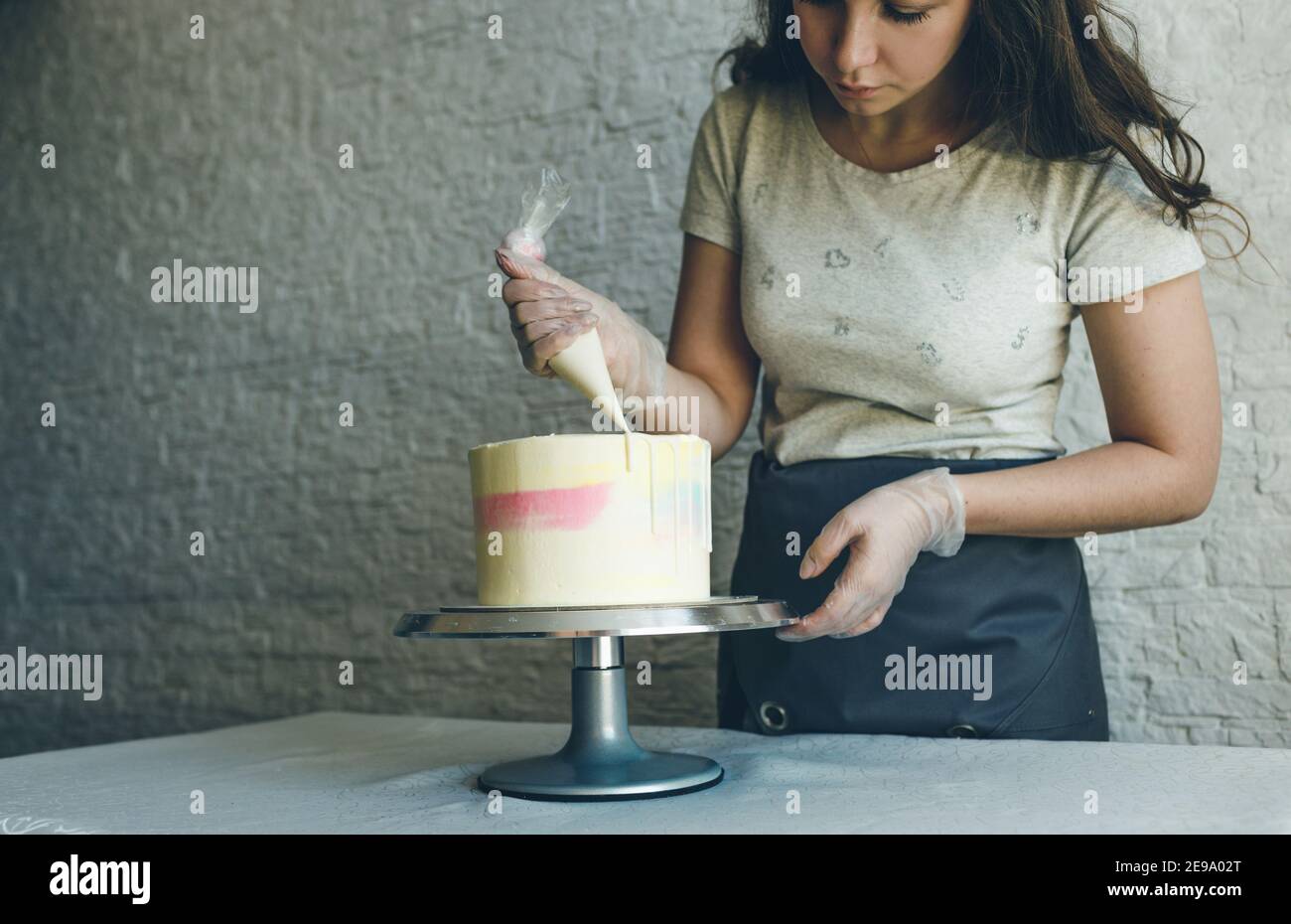 Une Patisserie Chef Fille Fait Un Gateau De Mariage Avec Ses Propres Mains Et Presse La Creme Sur Les Couches Du Gateau Un Chef Patissier Prepare Une Creme Rose A L Aide D Un