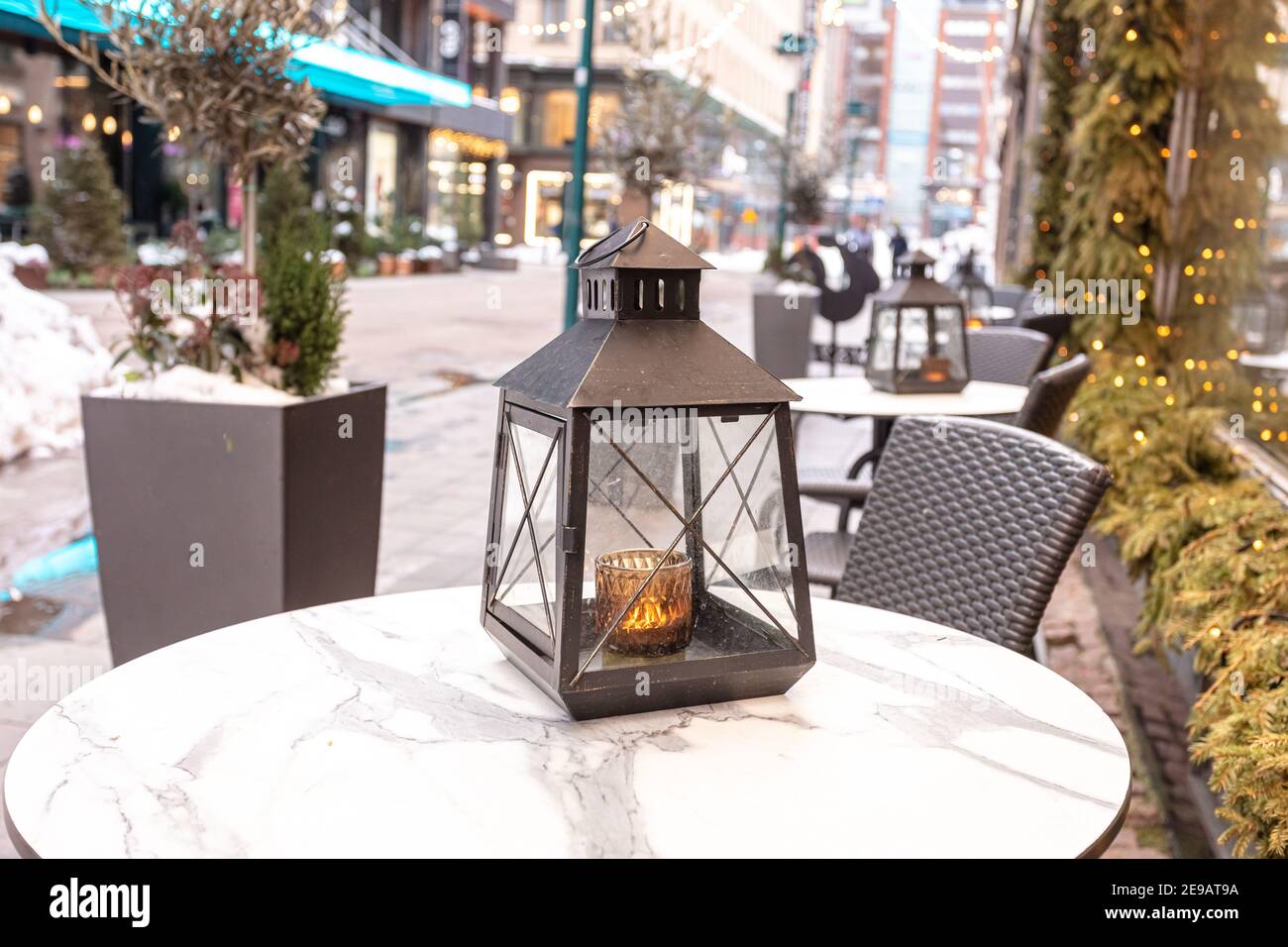 Lanterne dans la neige sur la table. Rue café intérieur. Photo de haute qualité Banque D'Images