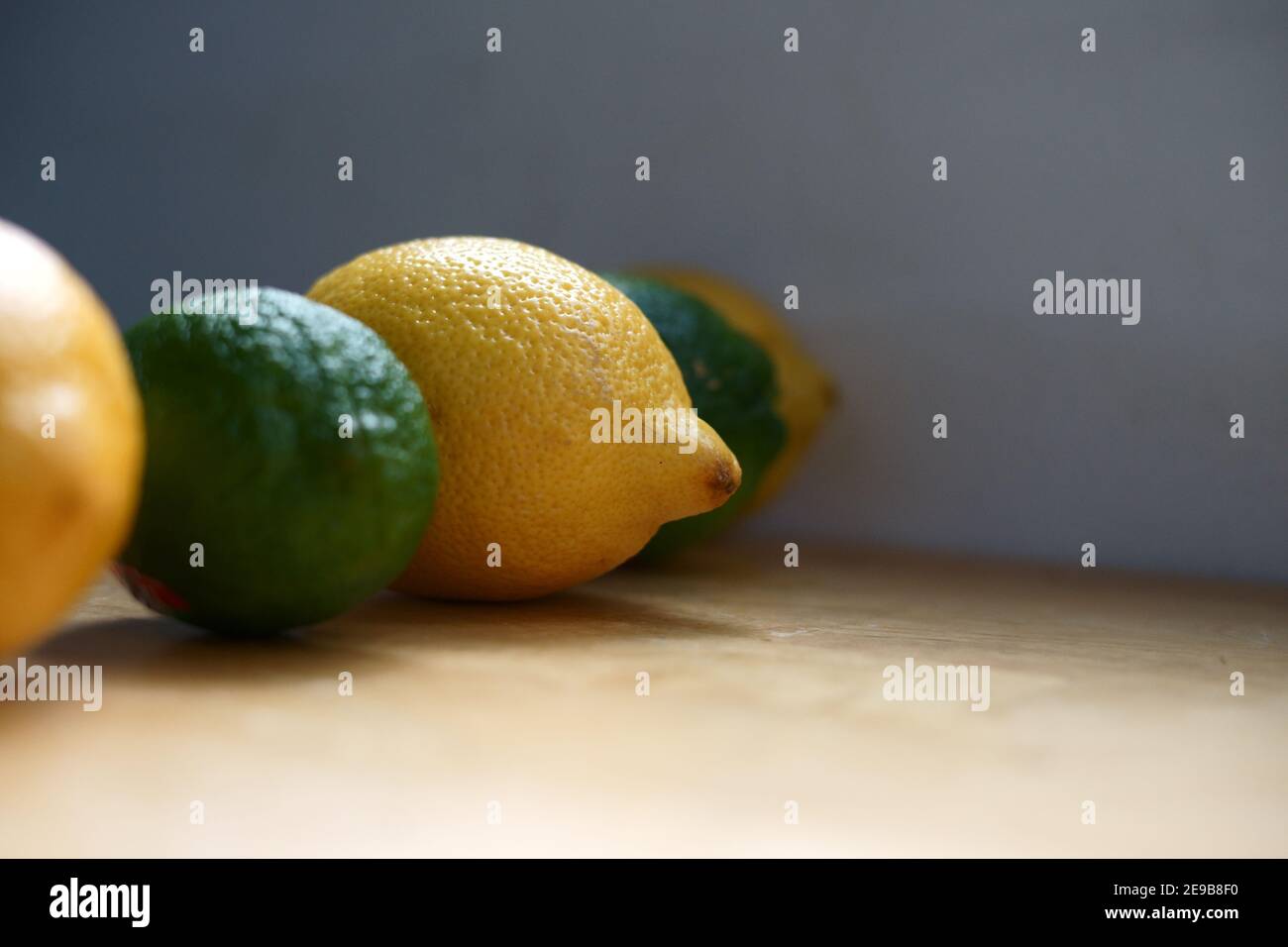 Portrait d'ingrédients frais et biologiques : une rangée de citron et de lime avec un accent sur le citron frais et biologique. Banque D'Images