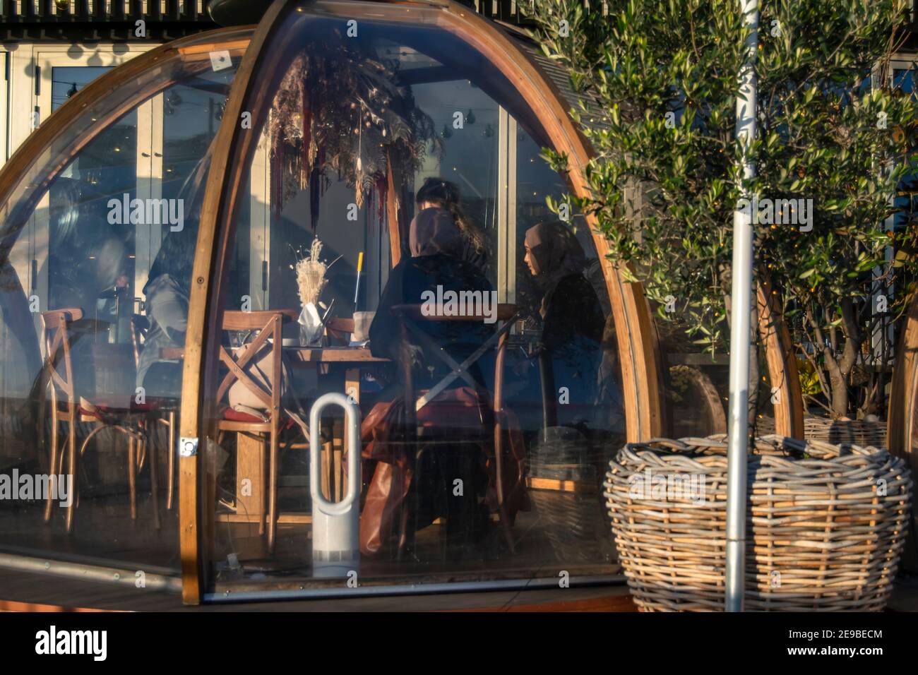 Londres, Royaume-Uni - 15 décembre 2020 : restaurant extérieur igloo salle de service séparée dans laquelle la serveuse sert des femmes musulmanes portant des burkas. Côté du fleuve du club COPPA Banque D'Images