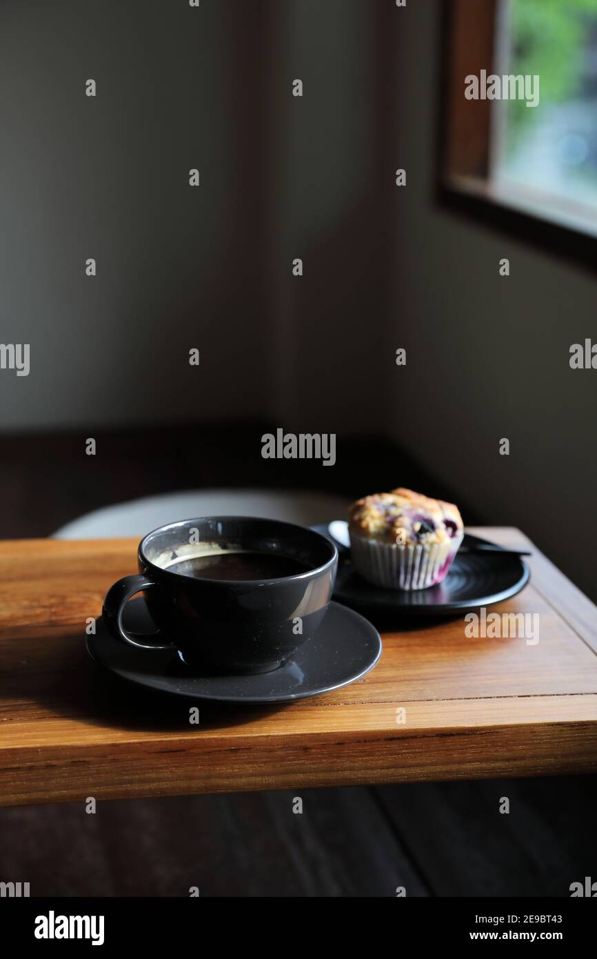 Tasse de café avec muffin sur table en bois dans le café local boutique Banque D'Images