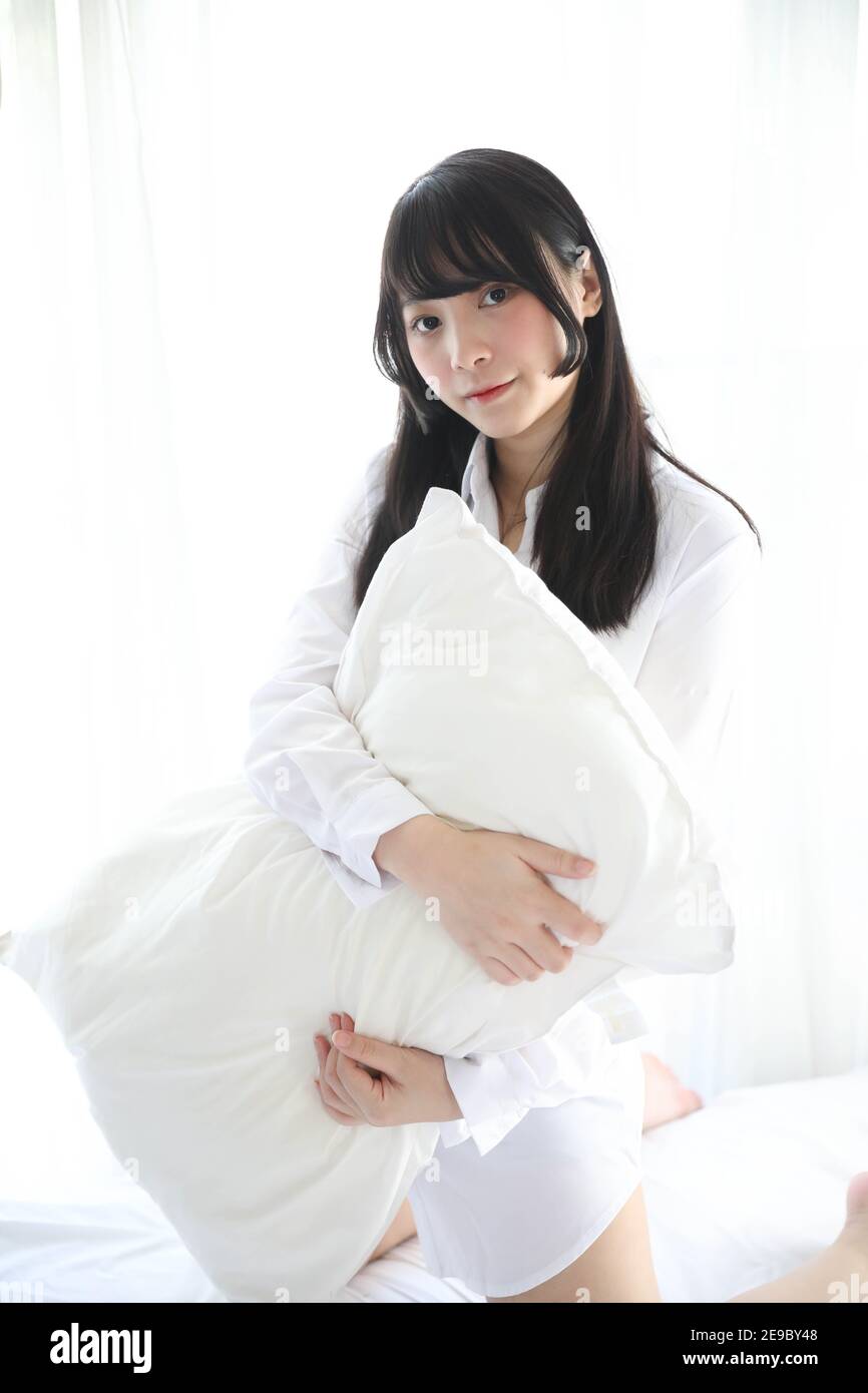 Portrait belle fille asiatique assise avec un oreiller dans la chambre blanche Banque D'Images