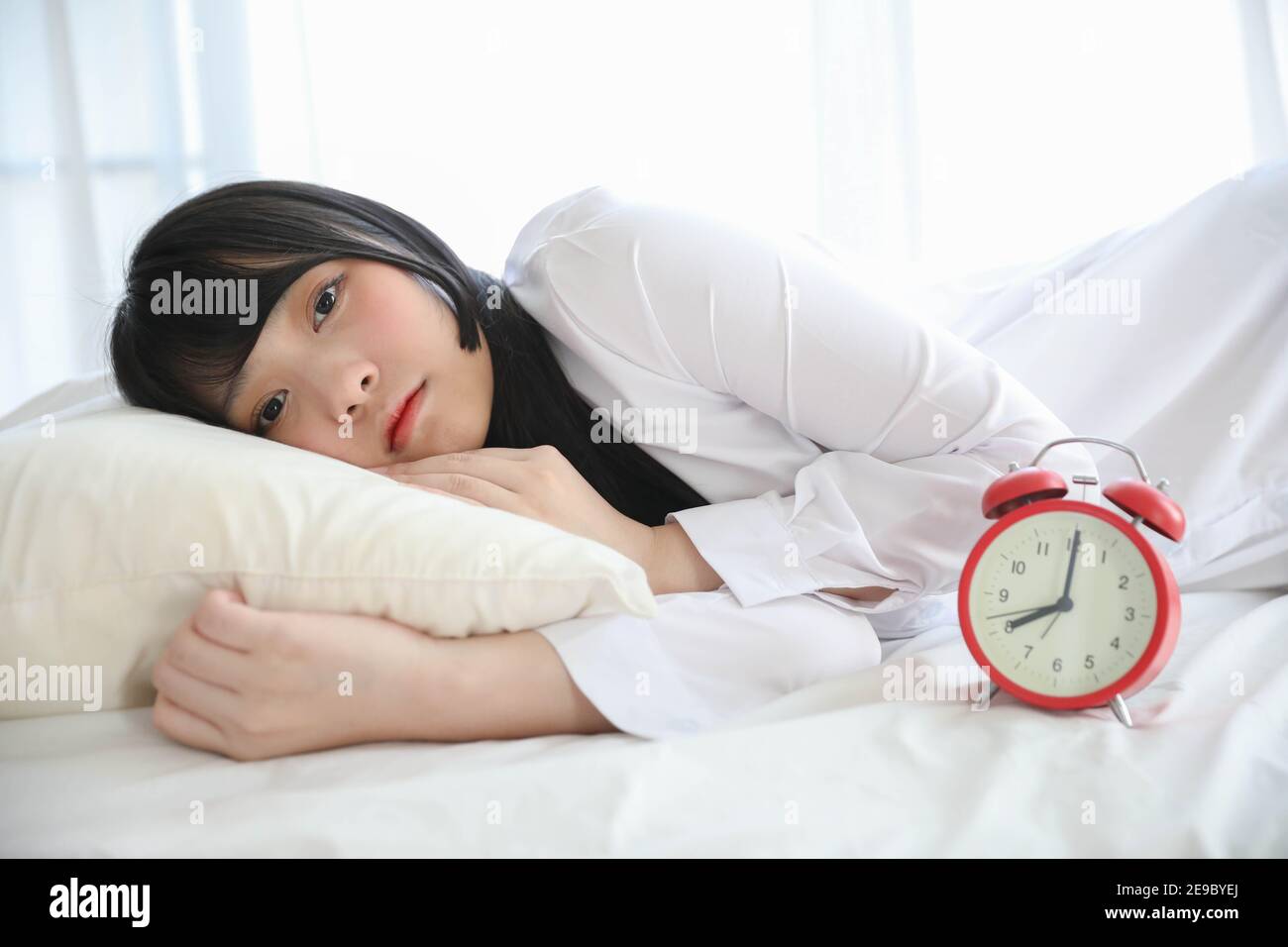 Portrait belle fille asiatique assise avec horloge à la chambre blanche Banque D'Images