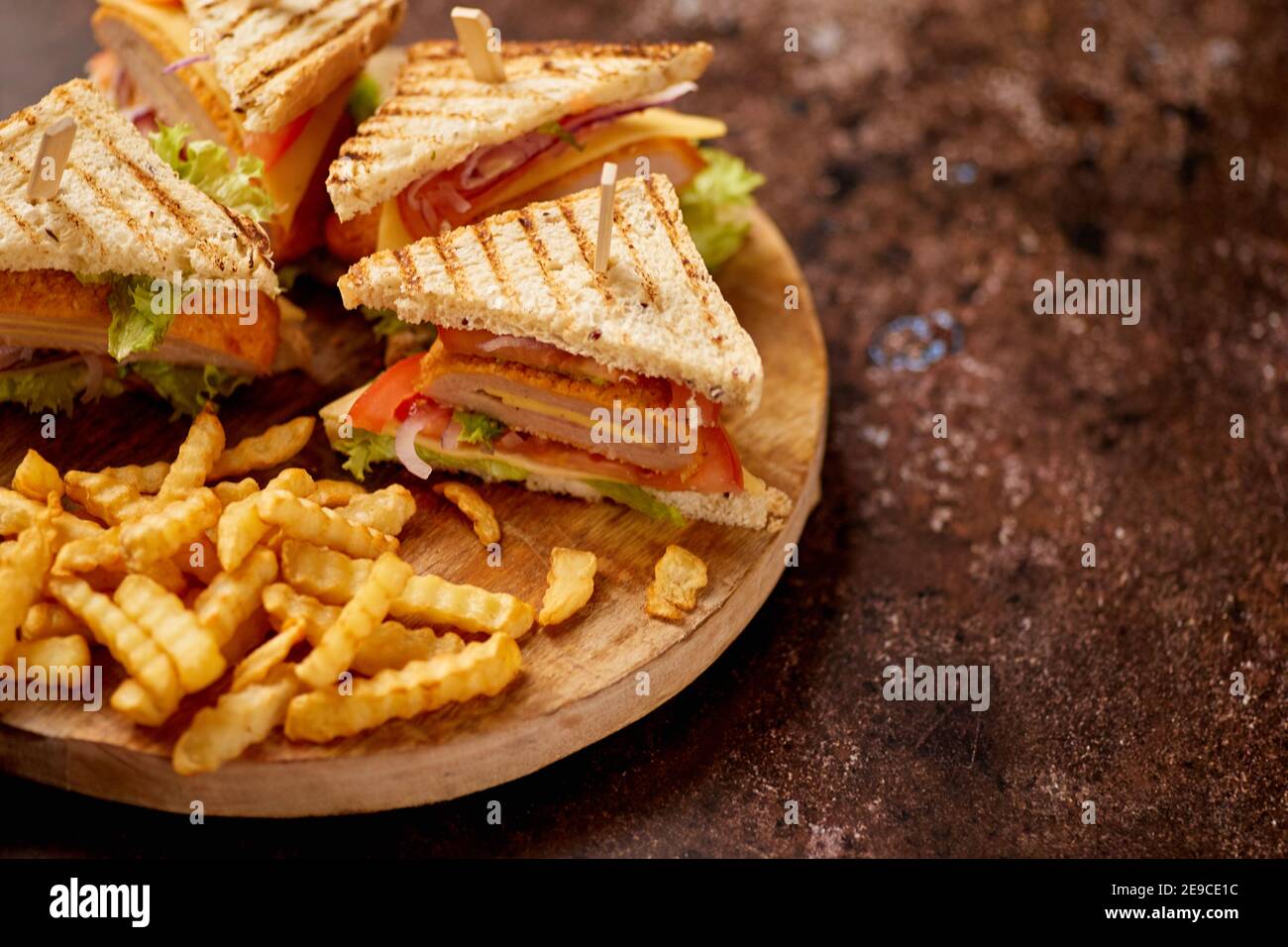 Les sandwichs Club sont servis sur une planche de bois. Avec des frites chaudes Banque D'Images