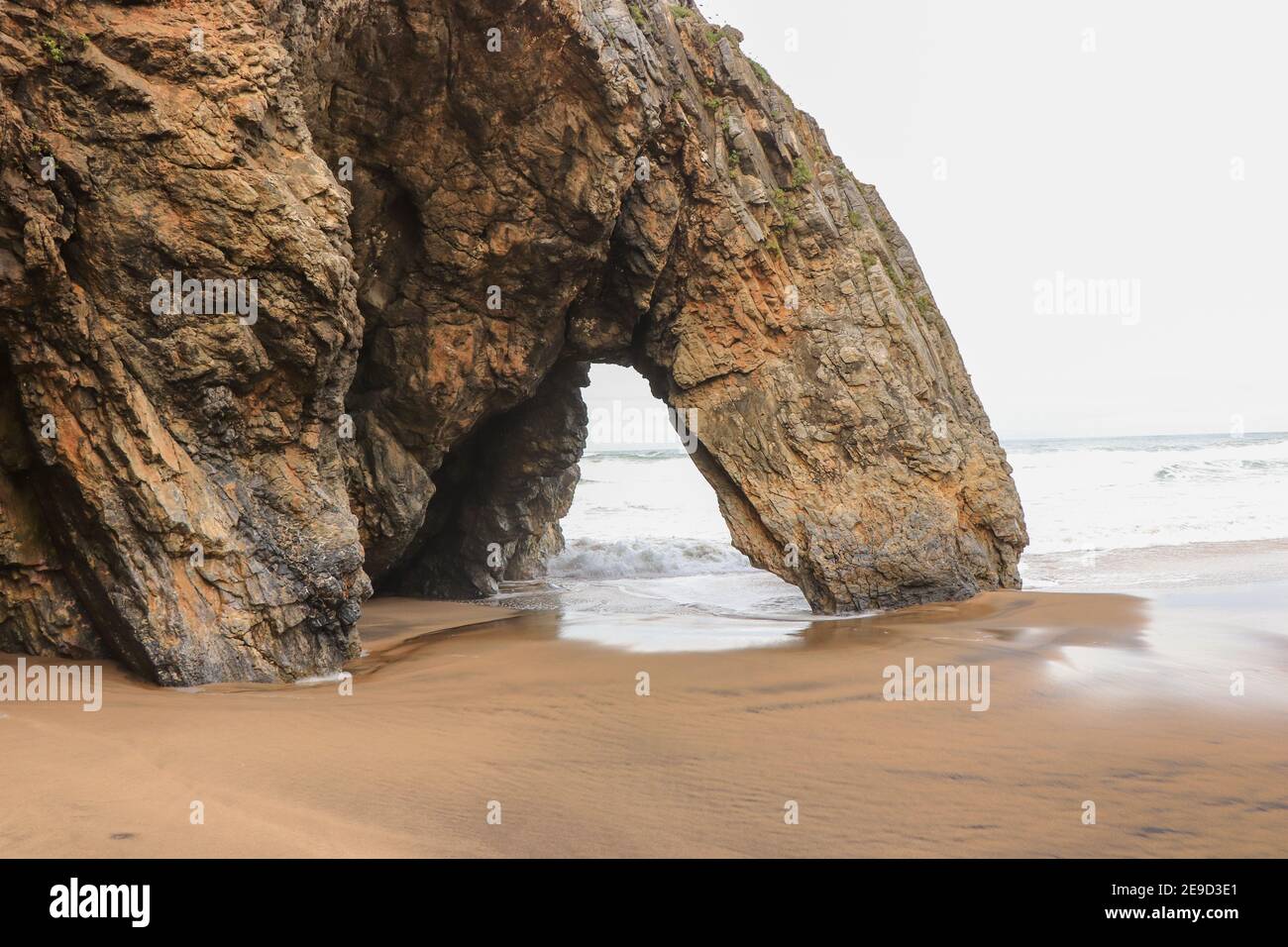 Belle pierre naturelle arche. Formation de roches dans une plage avec l'océan en arrière-plan. Banque D'Images