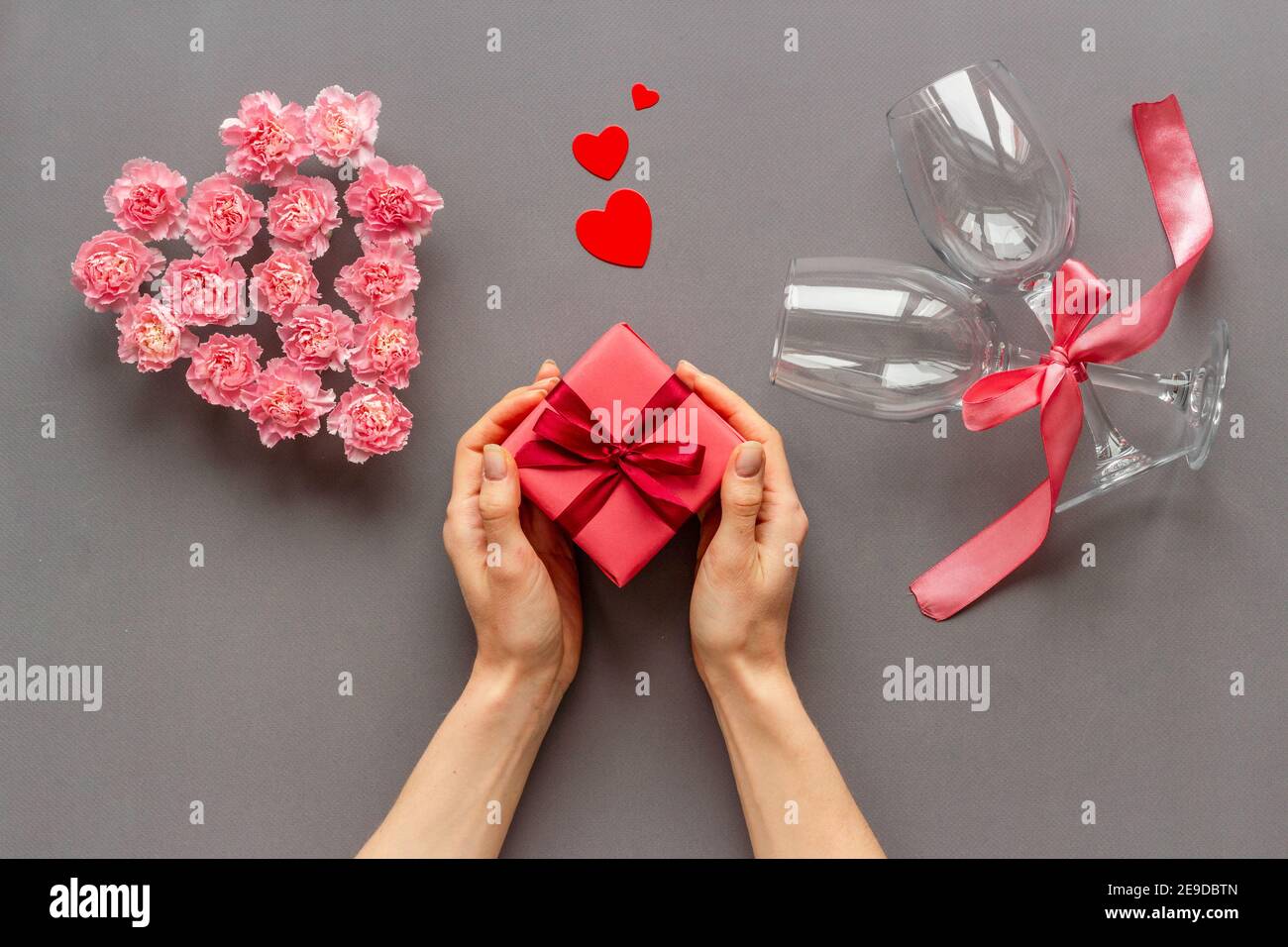 Boîte cadeau rouge entre les mains des femmes - célébration de la Saint-Valentin. Vue de dessus Banque D'Images
