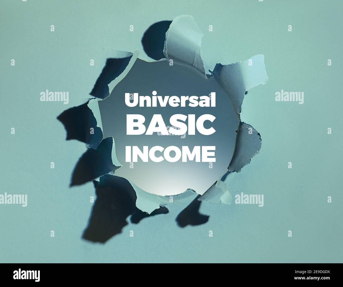 Texte revenu de base universel en caractères gras blancs apparaissant dans le trou de papier. Revenu de base inconditionnel fourni à tous les citoyens sans condition Banque D'Images