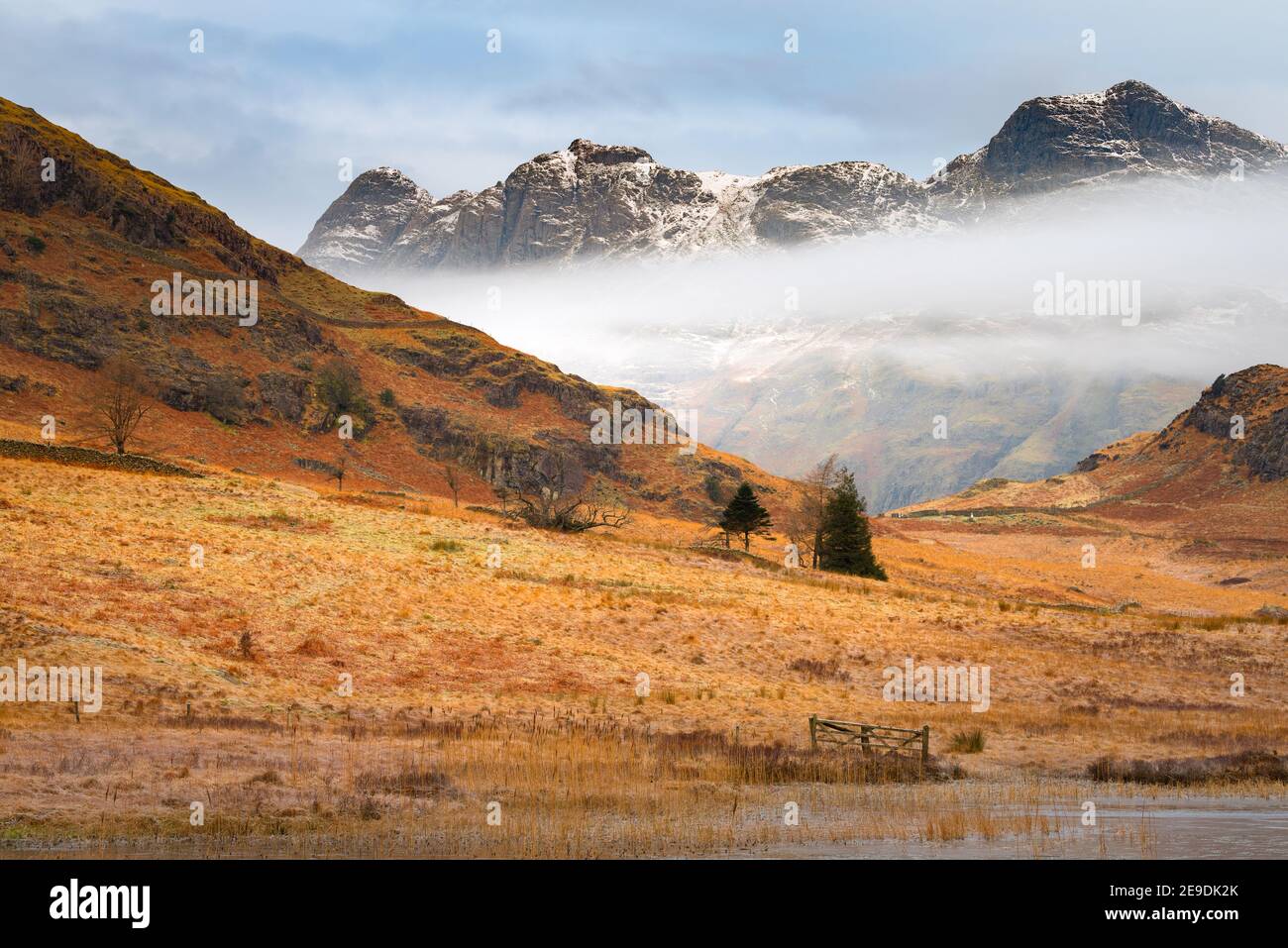 Brume basse qui persiste sous la chaîne de montagne enneigée l'après-midi d'hiver. Langdale Pikes, Lake District, Royaume-Uni. Banque D'Images