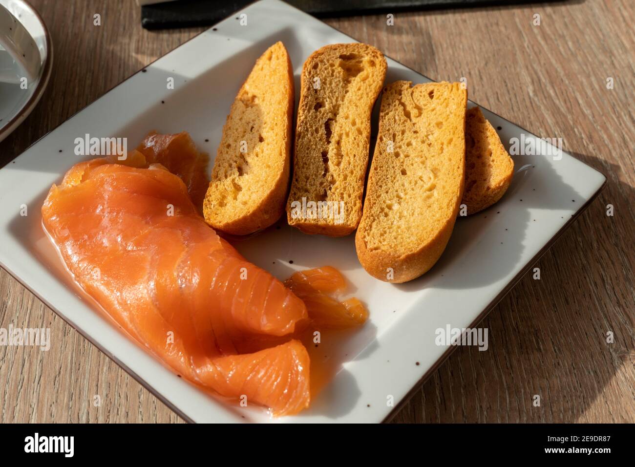Tranches de saumon fumé avec pain grillé sur une assiette carrée pour le  petit déjeuner Photo Stock - Alamy