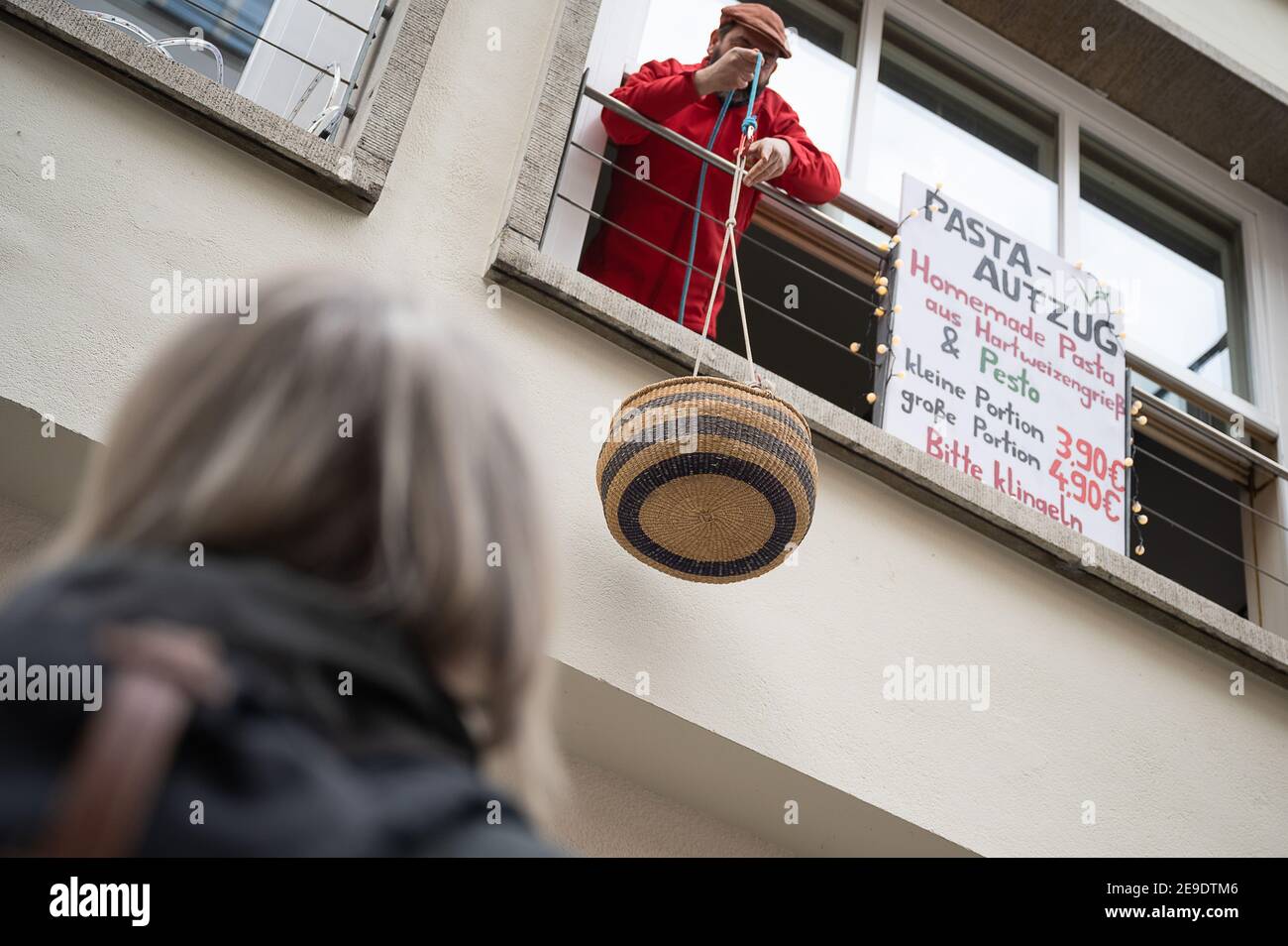 04 février 2021, Bade-Wurtemberg, Tübingen: Un restaurateur abaisse un panier de pâtes de son restaurant fermé. Avec l'« ascenseur des pâtes », le restaurant vend le déjeuner dans le confinement. (À dpa 'Corona Lockdown: L'opposition veut voir 'la lumière à la fin du tunnel') photo: Sebastian Gollnow/dpa Banque D'Images