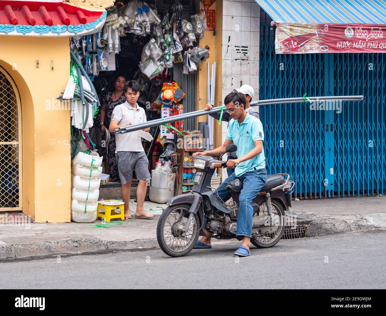 Homme à moto achetant des tuyaux en acier dans un magasin de matériel local à Ho Chi Minh ville, Vietnam. Banque D'Images