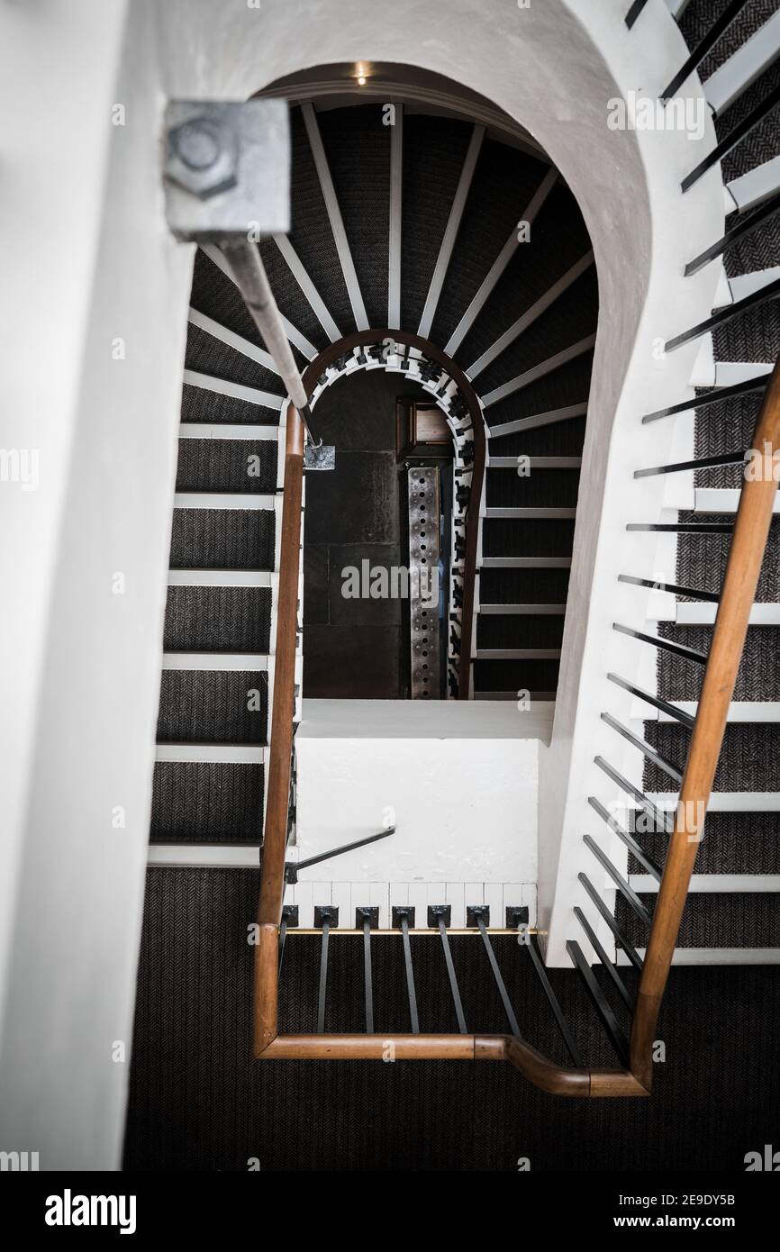 Escalier en colimaçon dans l'ancien manoir de trois étages, courbe vers plancher avec rampe en bois et radiateur de chauffage en acier ancien à le fond Banque D'Images