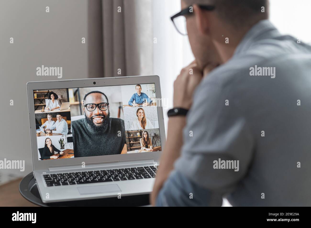 Remue-méninges, réunion vidéo en ligne, conférence virtuelle avec collègues multiethniques, employé, collègues. Vue sur l'épaule d'un gars sur un écran avec Banque D'Images