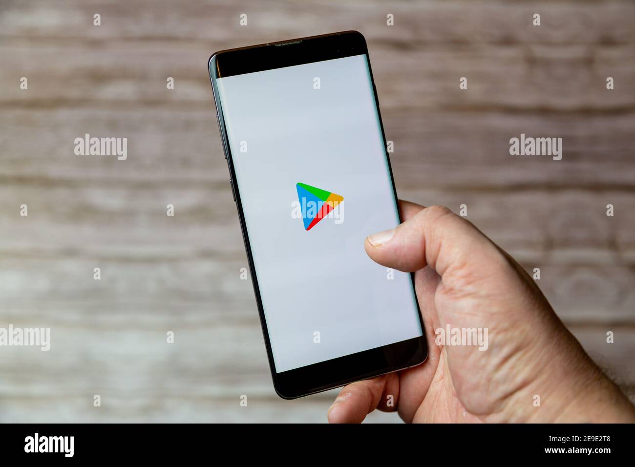 Une main tenant un téléphone portable ou un téléphone cellulaire avec L'application Google Play Store à l'écran Banque D'Images