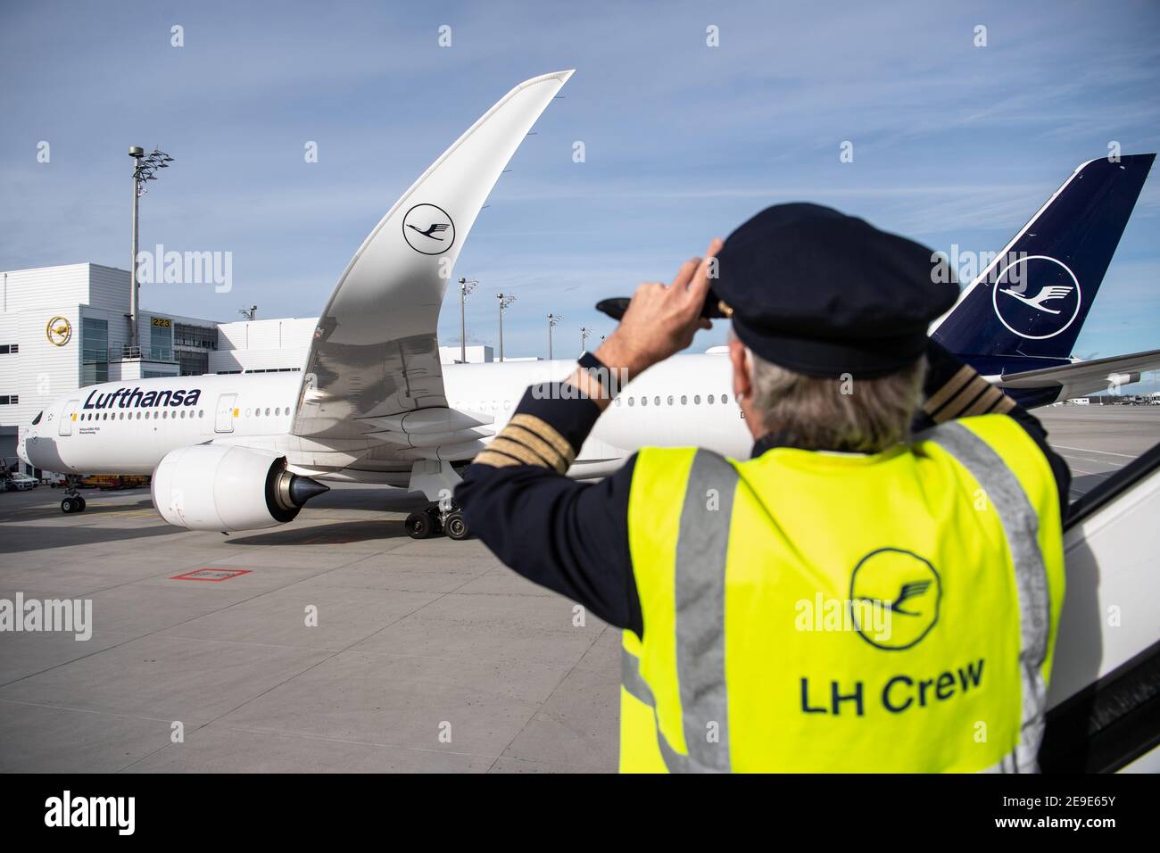Munich, Allemagne. 04e fév. 2021. Un homme portant une veste avec  l'inscription « LH Crew » prend une photo d'un Airbus A350-900 après  l'atterrissage après le plus long vol sans escale de