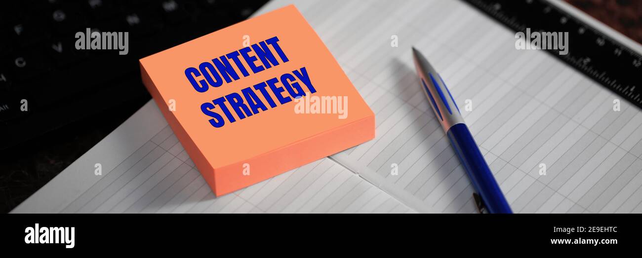 Stratégie de contenu. Le texte est écrit sur un autocollant jaune à côté du stylo et du journal. Concept de support de marketing numérique Banque D'Images