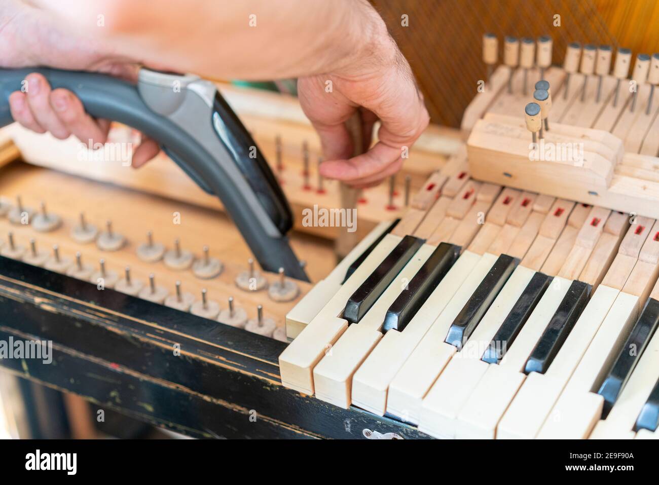 Installation d'un vieux piano. Le maître répare un vieux piano. Nettoyage en profondeur du piano. Mains d'un professionnel réparant et réglant un vieux piano Banque D'Images