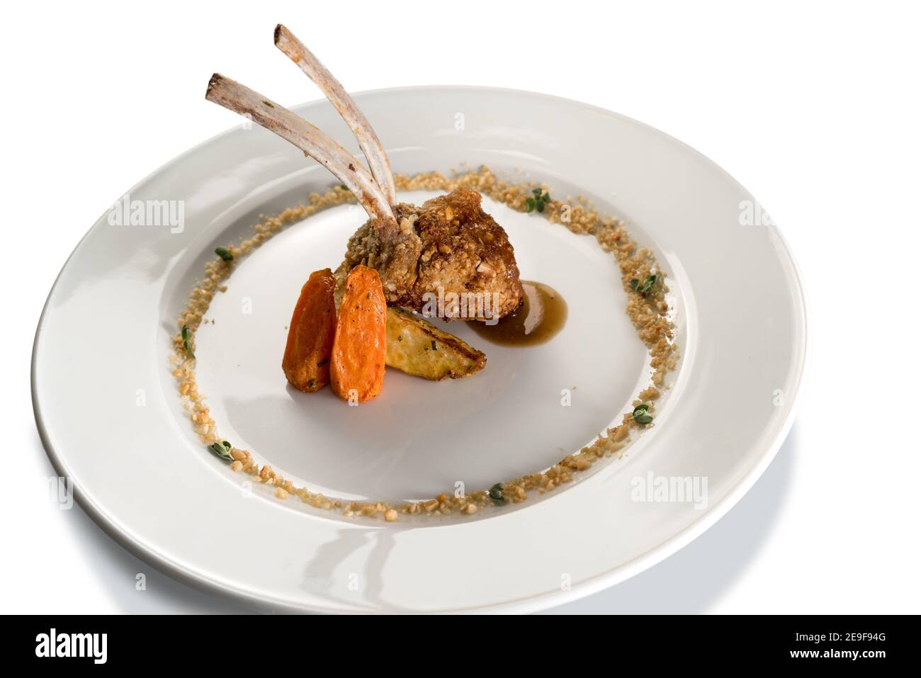 côtelettes d'agneau dans une croûte de noisettes dans un plat blanc isolé sur blanc Banque D'Images