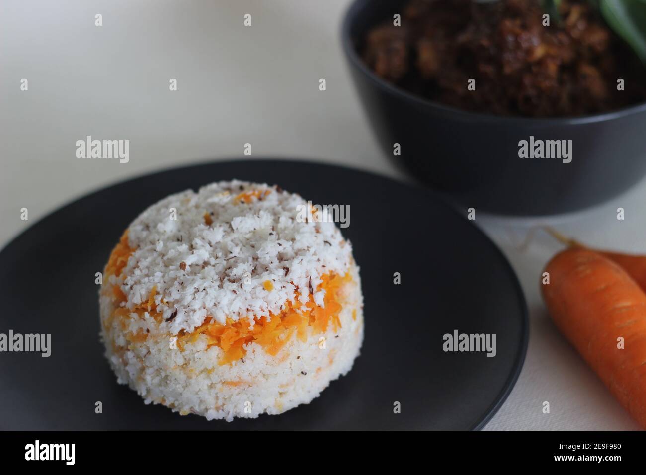 Puttu de carottes, une variété de gâteau à la vapeur de riz Kerala en ajoutant des carottes râpées servies avec du poulet rôti préparé dans le style Kerala avec de l'huile de coco Banque D'Images