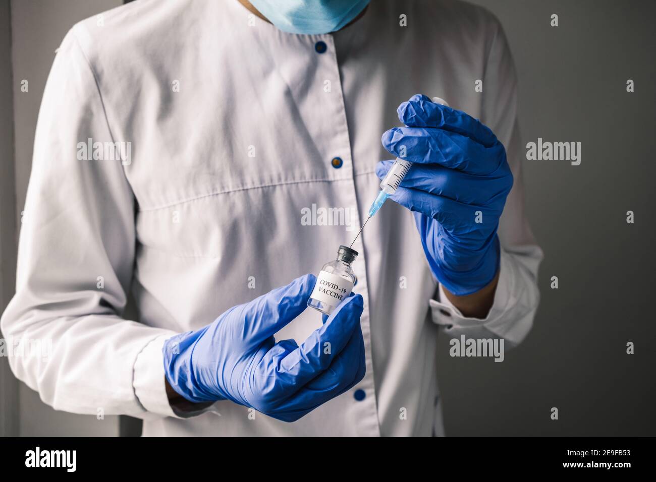 Gros plan le médecin portant des gants bleus aspire le vaccin Covid-19 dans une seringue, en préparation de la vaccination. Banque D'Images