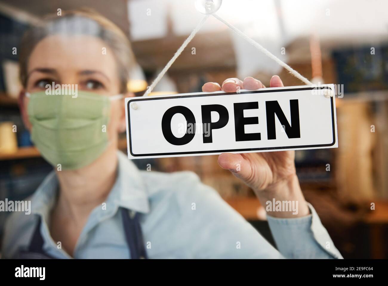 Femme propriétaire de petite entreprise portant masque tournant rond Ouvrir l'affiche pendant une pandémie de santé Banque D'Images