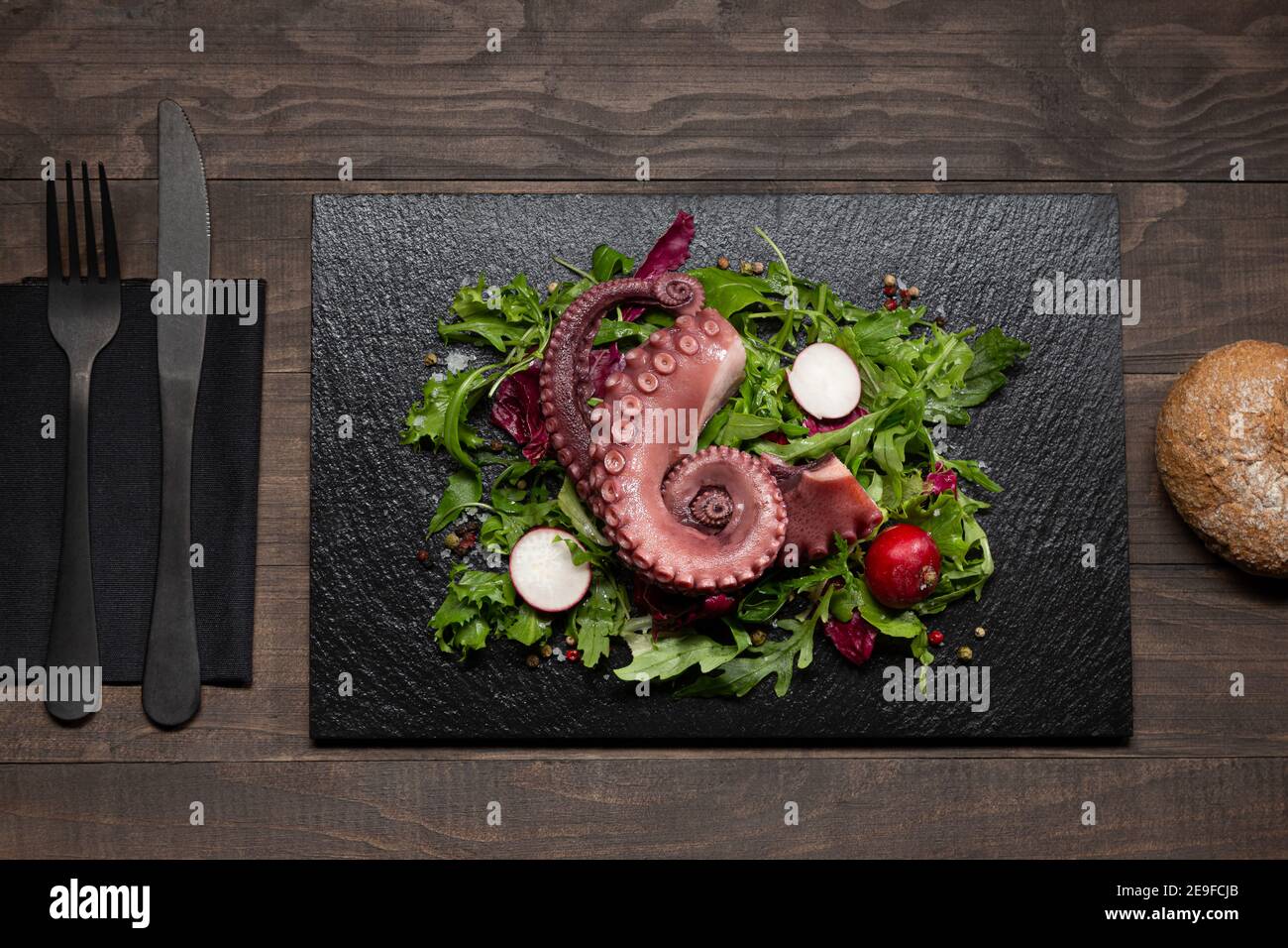ragoût les tentacules de poulpe avec une salade sur une assiette en pierre sur une table en bois. Vue de dessus. Banque D'Images