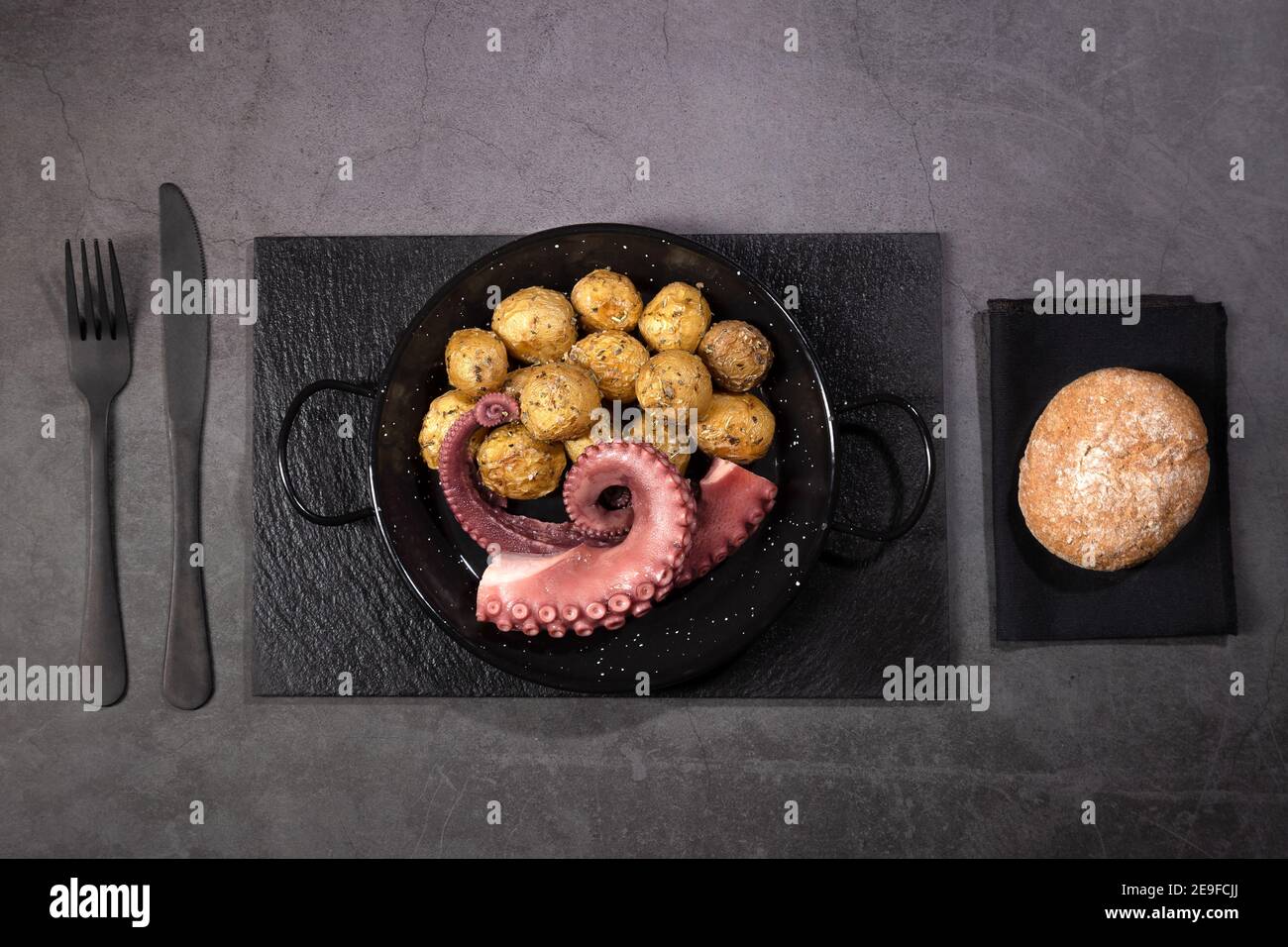 Ragoût de tentacules de poulpe avec des pommes de terre sur une plaque à poêle sur fond sombre vue de dessus. Banque D'Images