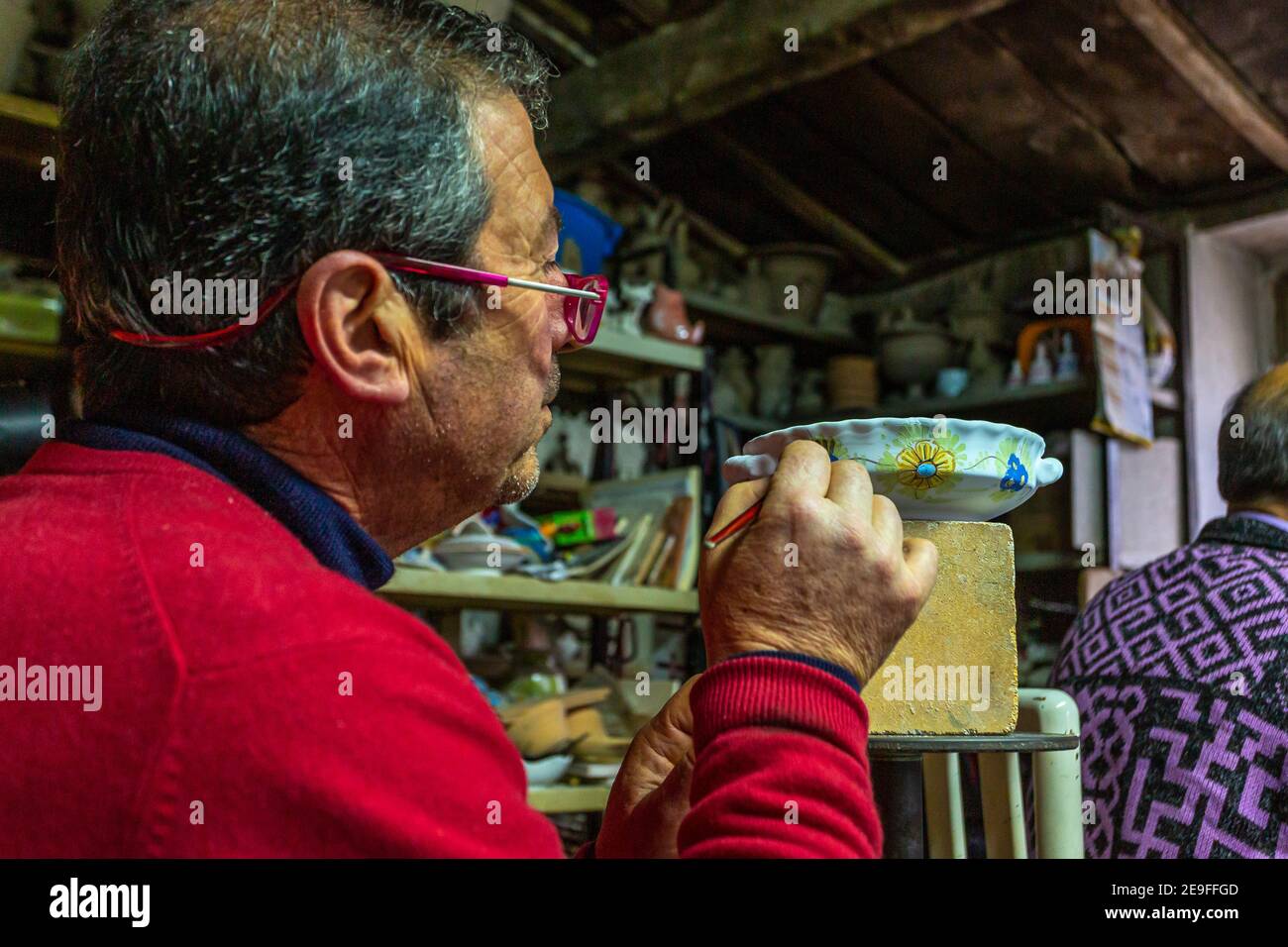 Homme travaillant dans son atelier de poterie, peignant sur une tasse d'argile. Peinture céramique Banque D'Images