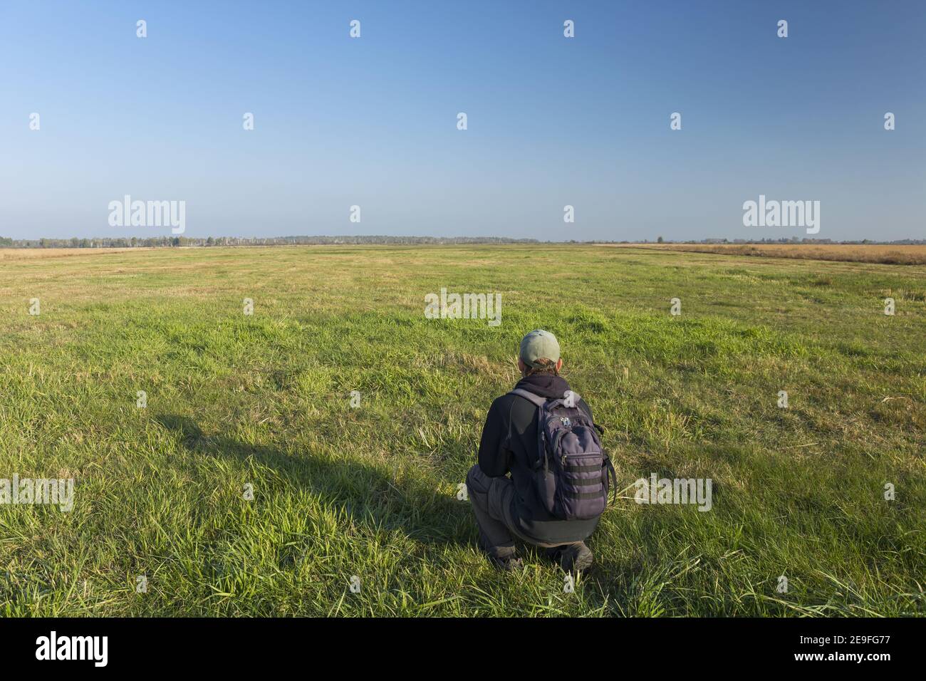 Un voyageur avec un sac à dos crouch sur la prairie Banque D'Images