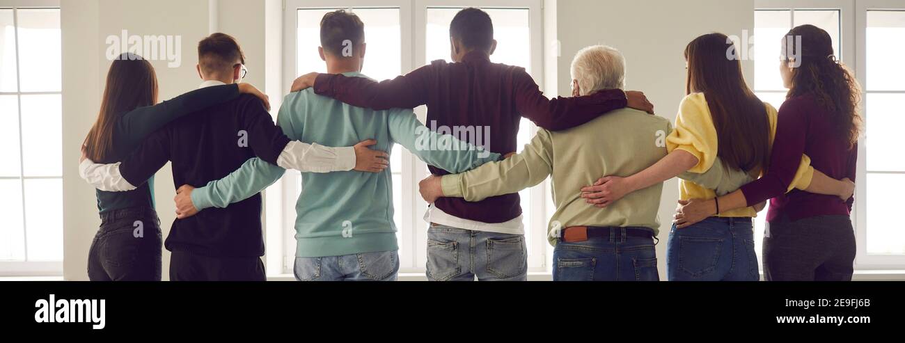 Une équipe de personnes se tient debout dans une rangée avec leur dos à la caméra et regardant par la fenêtre. Banque D'Images