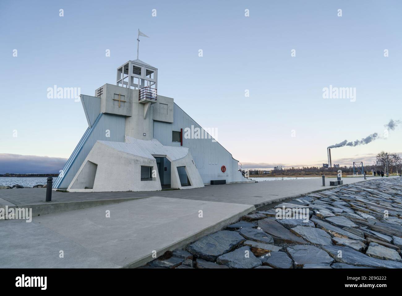 Vue latérale du phare de Nallikari à Oulu, Finlande, sur la mer Baltique. Tour maritime à l'extrémité de la jetée pavée avec fumée d'une usine dans l'arrière-gro Banque D'Images