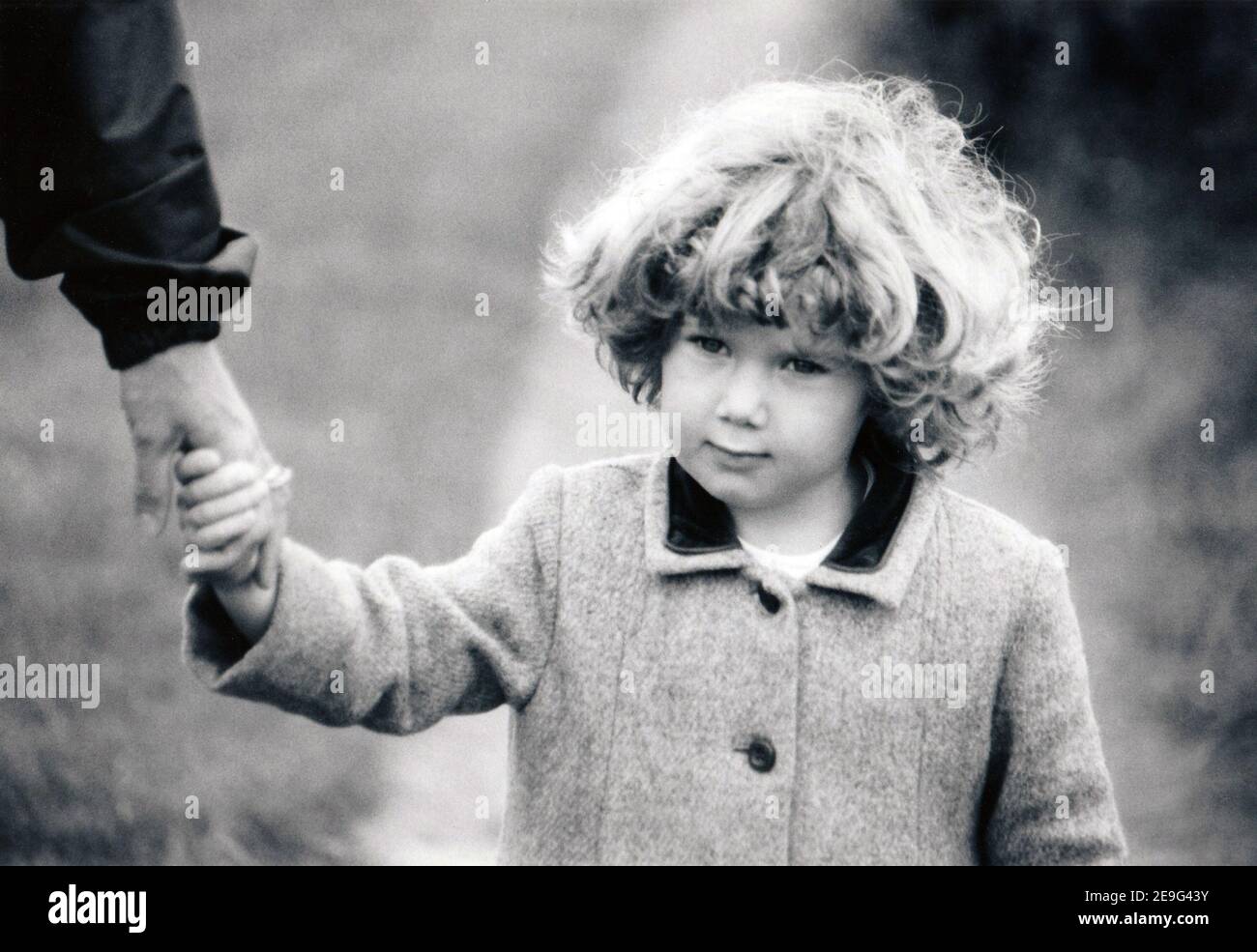 vintage après la guerre portrait monochrome de petite fille en train de cacher la main d'adulte, c. années 1950 Banque D'Images
