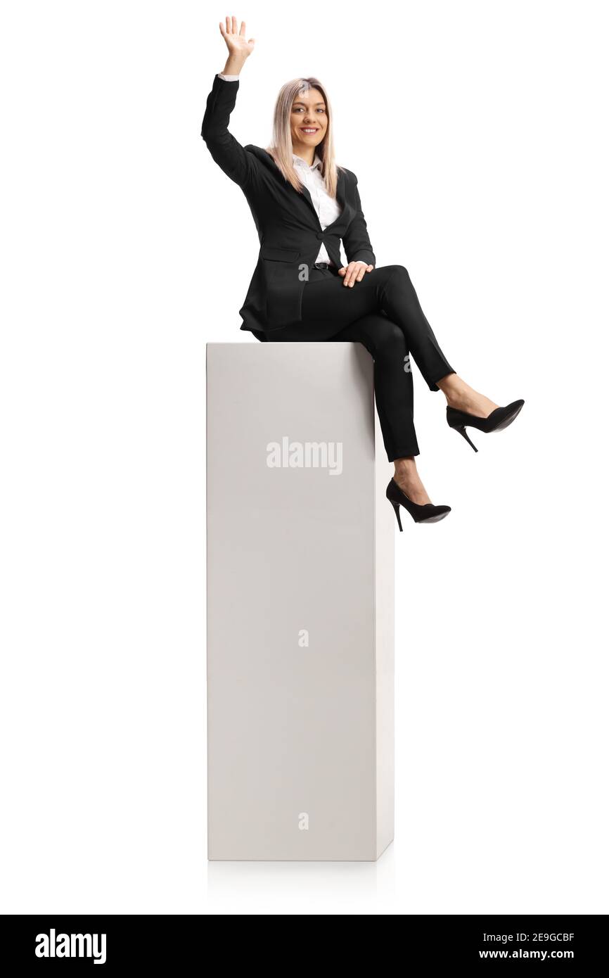 Jeune femme assise sur une colonne et agitant à la caméra isolé sur fond blanc Banque D'Images