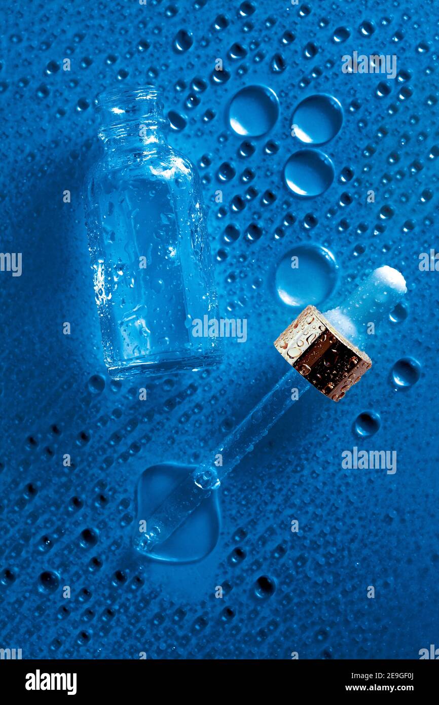 fond d'eau bleu avec flacon de cosmétiques en verre et compte-gouttes pour médicaments. couche hydratante à plat. Banque D'Images