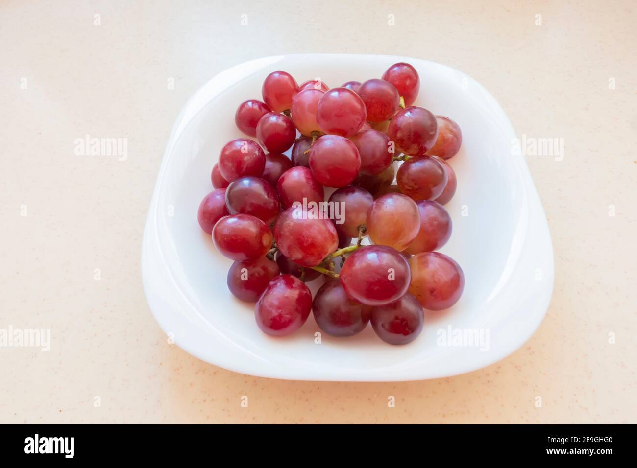 Raisins rouges biologiques sur plaque blanche Banque D'Images