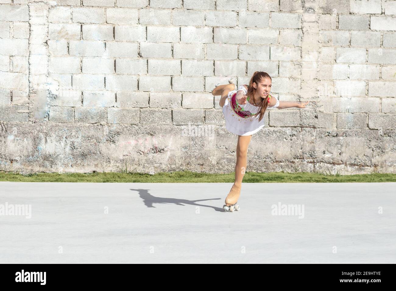 Adolescente faisant une figure à roulettes patinage artistique patinage artistique sur une jambe de la patinoire. Banque D'Images