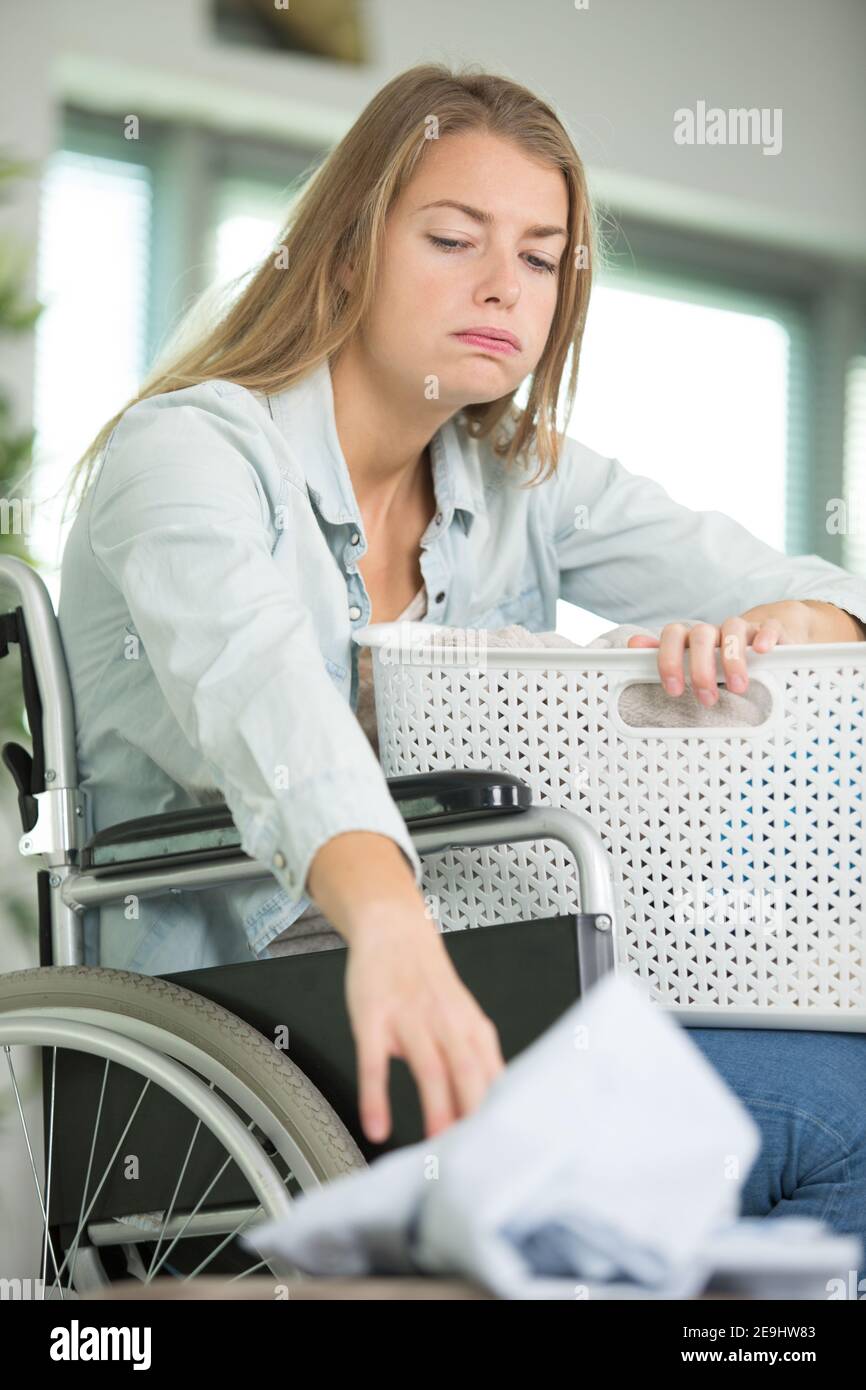 femme bouleversée en fauteuil roulant avec un panier de vêtements Banque D'Images