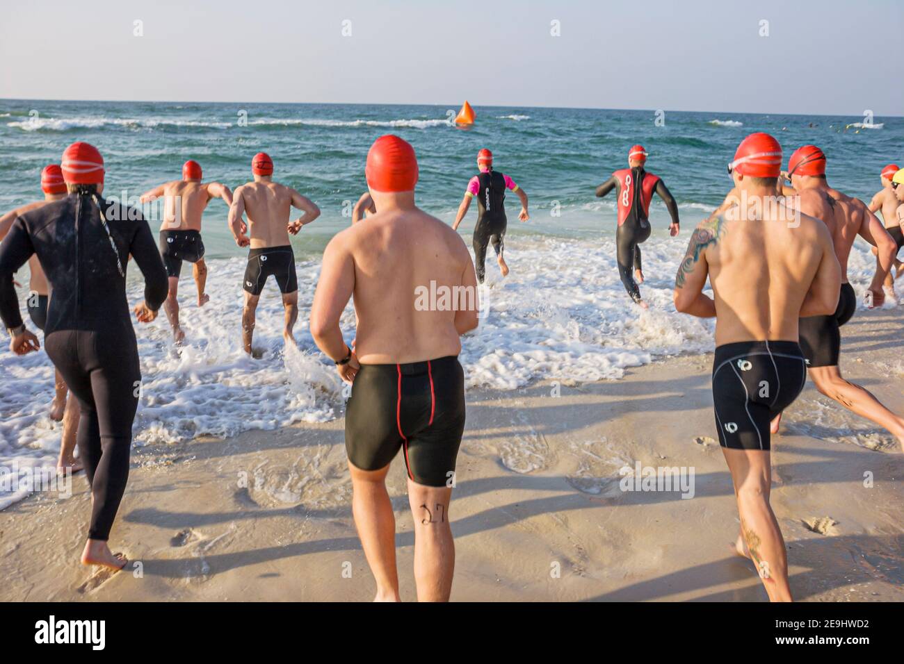 Alabama Golfe du Mexique Côte Florabama Mullet Man Triathlon, concurrents nageurs courant dans l'eau de surf hommes, Banque D'Images