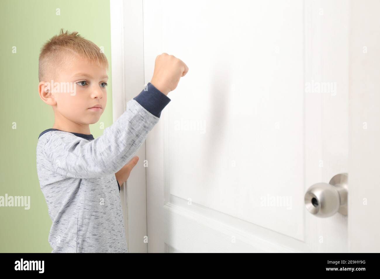 Un petit garçon mignon qui frappe à la porte Photo Stock - Alamy