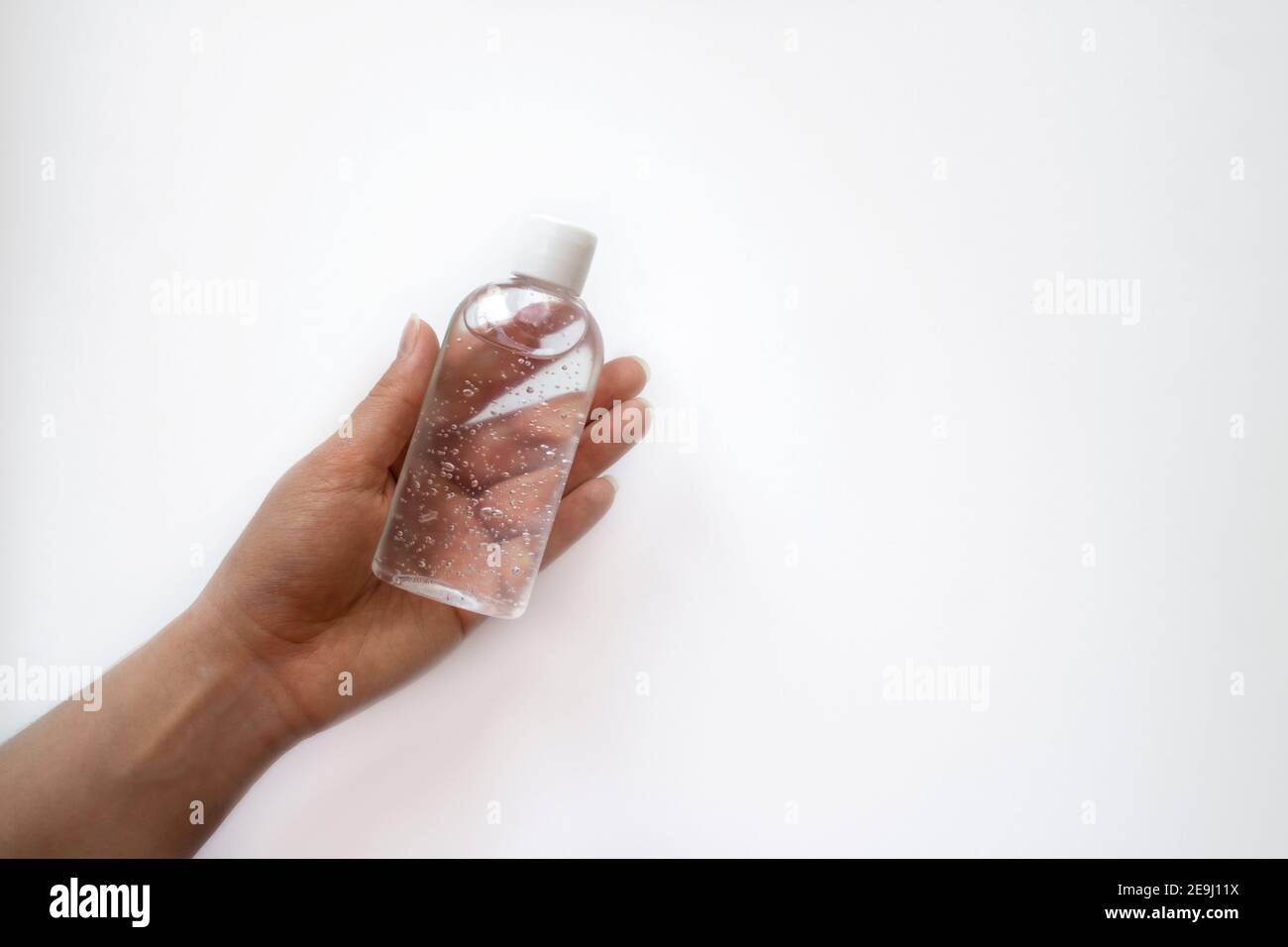 Pot avec du gel antiseptique dans une main sur fond blanc. Nettoyant antimicrobien. Banque D'Images