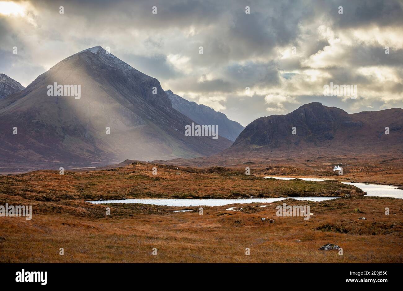 Île de Skye, Écosse : un puits de soleil traverse la montagne de Glamanig avec la rivière Sligachan en premier plan. Banque D'Images