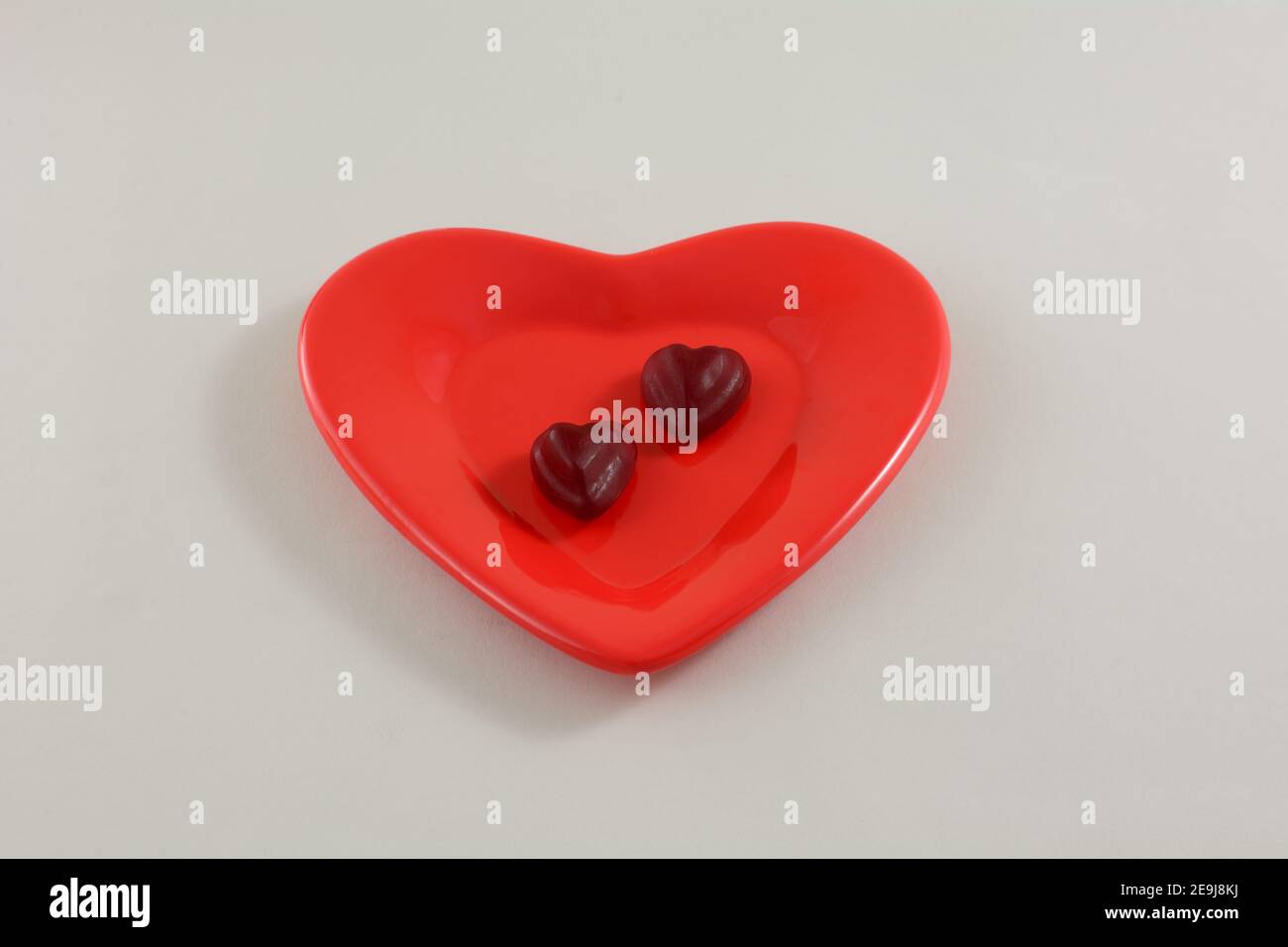 Deux bonbons rouges en forme de coeur de cerise pour la Saint-Valentin rouge plaque en forme de cœur sur fond blanc Banque D'Images